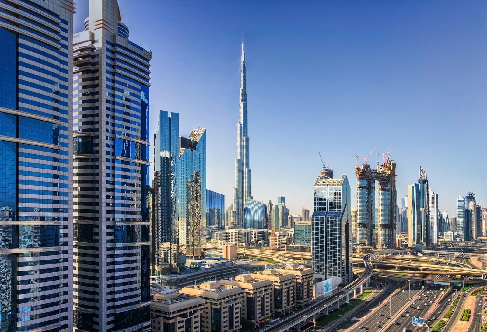 Burj Khalifa rising above adjacent Downtown Dubai residential and hotel towers in daylight