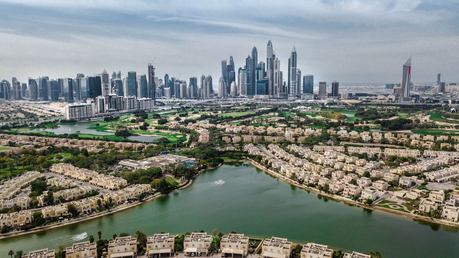 Villa community and lake with the Dubai skyline beyond