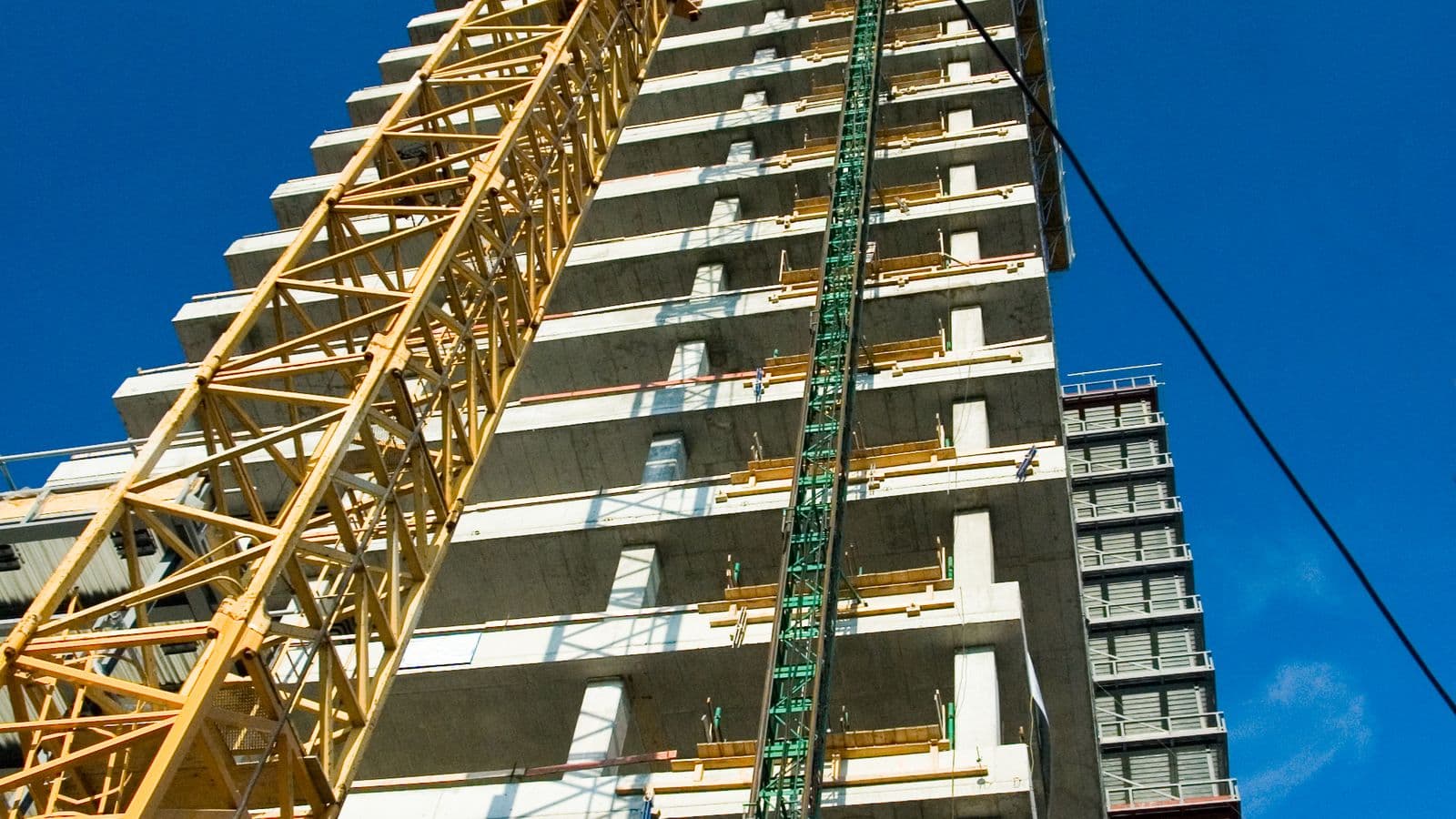 Concrete frame of a residential tower under construction beside a crane