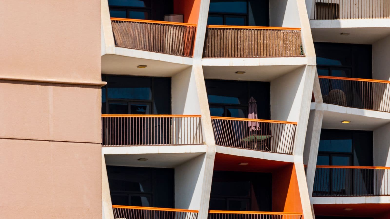 Angled apartment balconies with orange railings on a residential facade