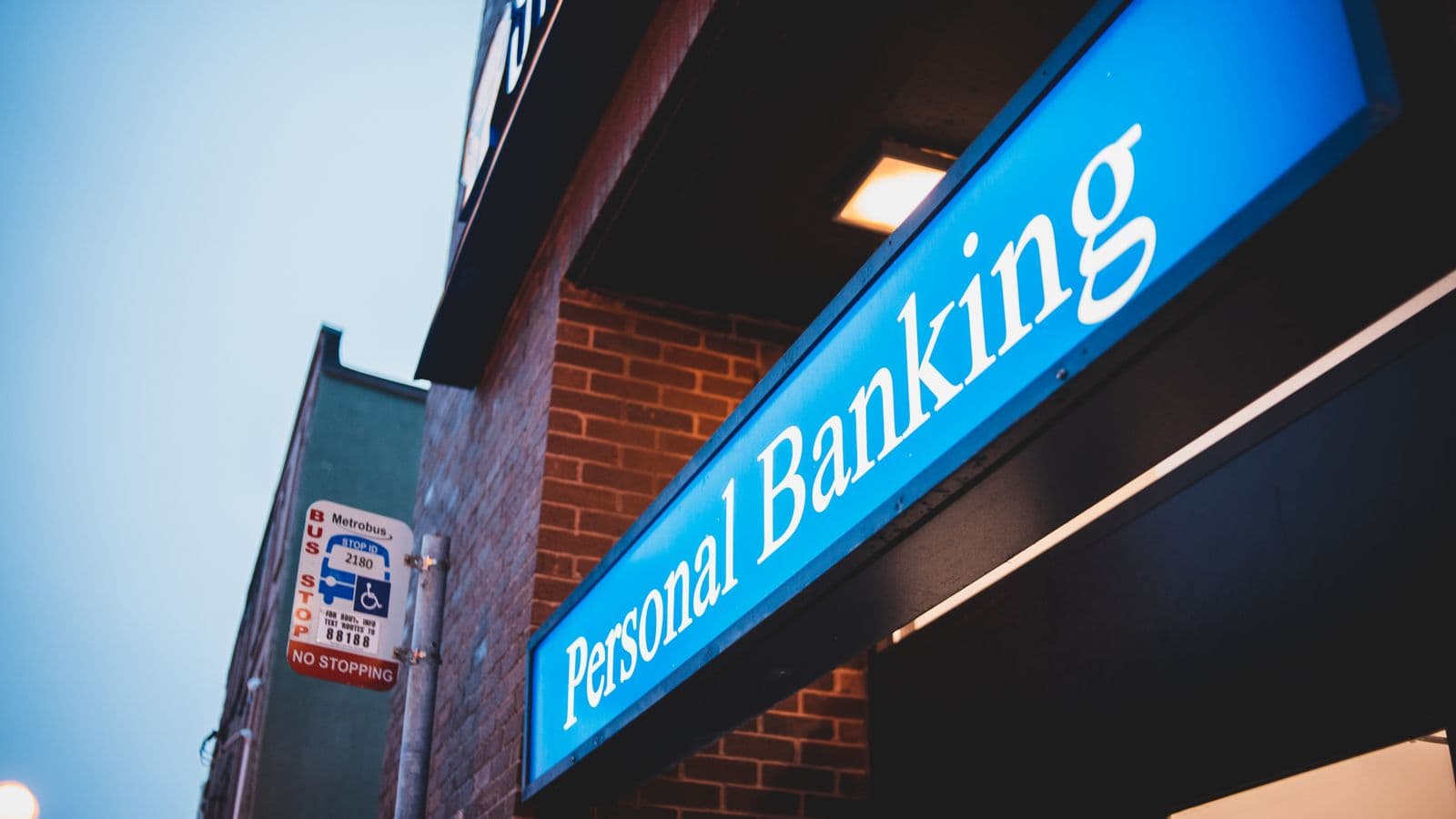 Illuminated Personal Banking sign outside a bank building at dusk